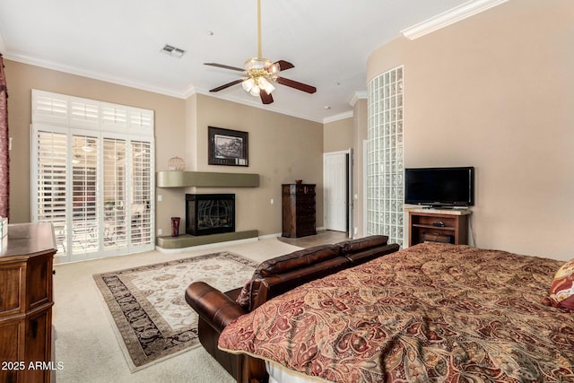 bedroom with visible vents, ornamental molding, a glass covered fireplace, ceiling fan, and carpet