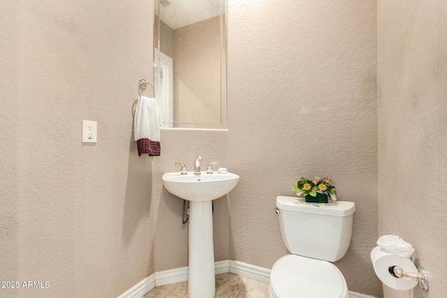 bathroom featuring toilet, tile patterned floors, and baseboards