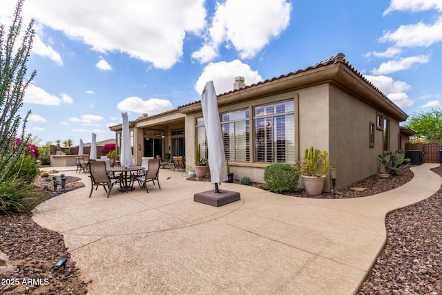 back of property with fence, central AC, stucco siding, outdoor dining area, and a patio