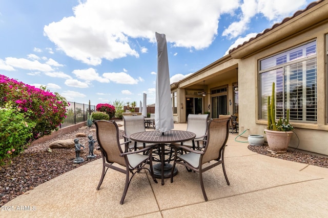 view of patio featuring ceiling fan, fence, and outdoor dining space