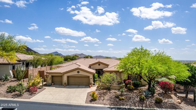 mediterranean / spanish home with fence, a garage, stucco siding, a tiled roof, and driveway