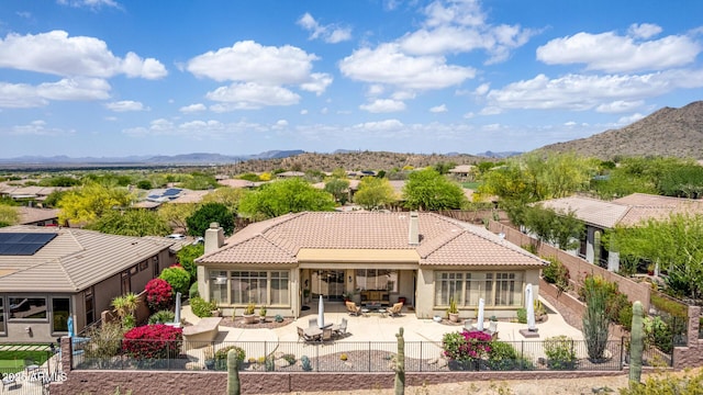 rear view of house with a tiled roof, a mountain view, a fenced backyard, a patio, and stucco siding