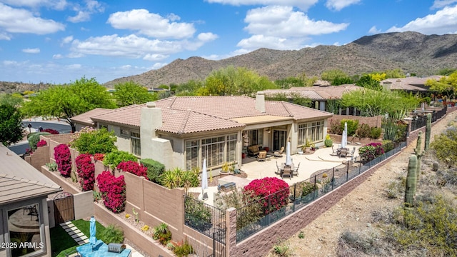rear view of property with a chimney, a tile roof, a patio area, a fenced backyard, and a mountain view