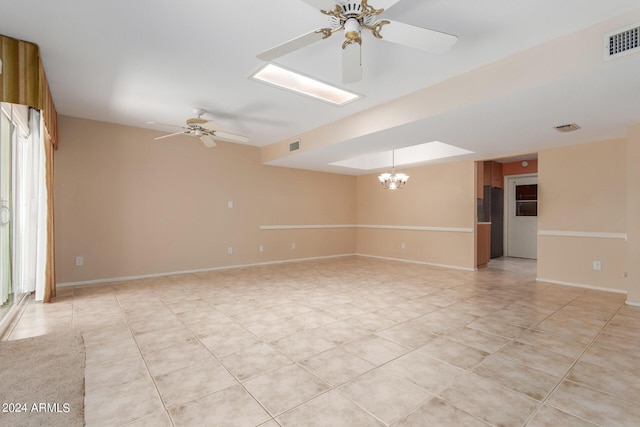 tiled spare room with ceiling fan with notable chandelier