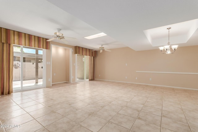 tiled empty room featuring a tray ceiling and ceiling fan with notable chandelier