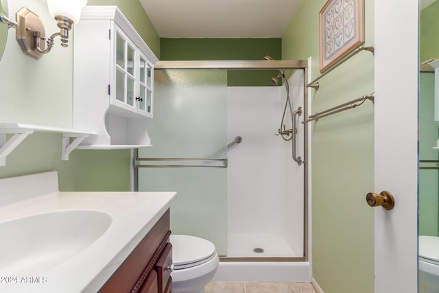 bathroom featuring tile patterned flooring, vanity, an enclosed shower, and toilet