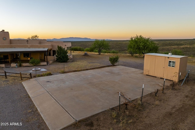 patio terrace at dusk featuring a mountain view and a storage shed