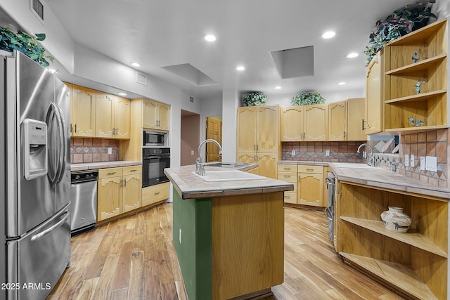 kitchen with black oven, built in microwave, stainless steel fridge, tile counters, and light wood-type flooring