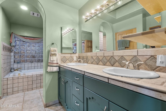 bathroom with vanity, backsplash, tile patterned flooring, and tiled bath