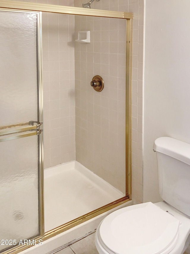 bathroom featuring toilet and a shower with door