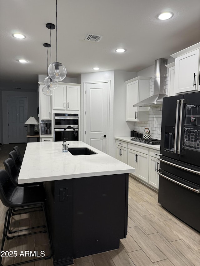 13342 W Lariat Ln, Peoria, AZ 85383 - kitchen featuring a center island with sink, wall chimney range hood, white cabinets, and black appliances