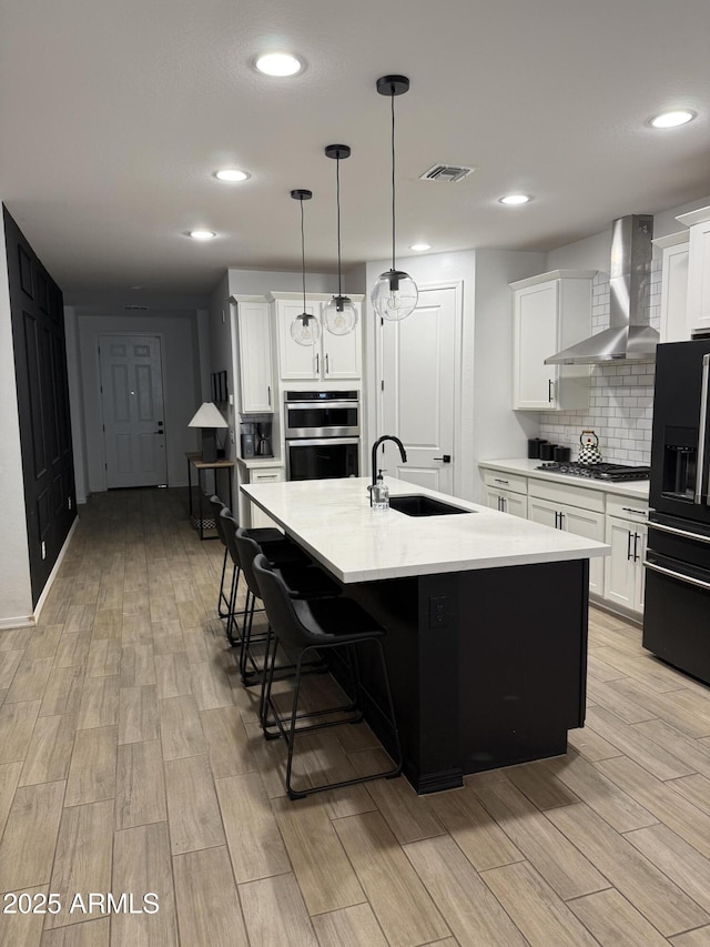 13342 W Lariat Ln, Peoria, AZ 85383 - kitchen featuring appliances with stainless steel finishes, decorative light fixtures, an island with sink, sink, and wall chimney range hood