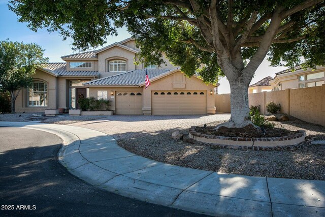 5281 W Quail Ave, Glendale, AZ 85308 - mediterranean / spanish-style house with fence, an attached garage, a tile roof, stucco siding, and driveway