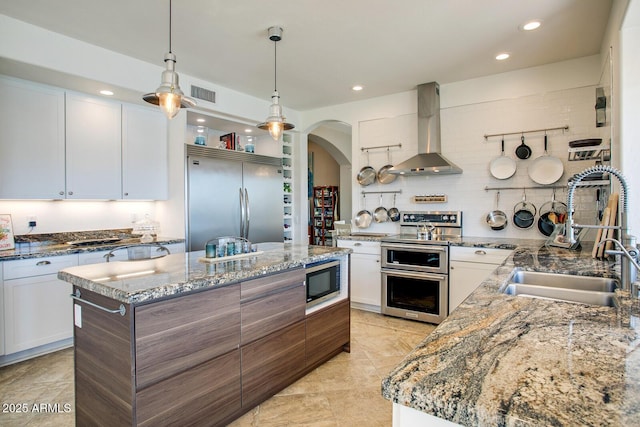 5281 W Quail Ave, Glendale, AZ 85308 - kitchen with wall chimney range hood, a sink, built in appliances, arched walkways, and a center island