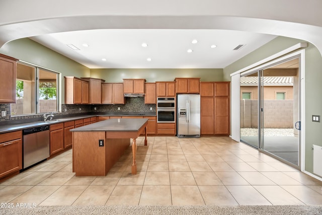 19245 W Pasadena Ave, Litchfield Park, AZ 85340 - kitchen featuring stainless steel appliances, decorative backsplash, a center island, a kitchen breakfast bar, and brown cabinets