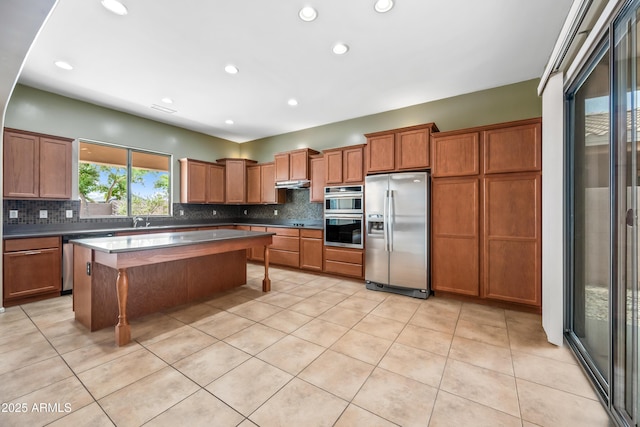 19245 W Pasadena Ave, Litchfield Park, AZ 85340 - kitchen featuring appliances with stainless steel finishes, brown cabinets, decorative backsplash, light tile patterned floors, and recessed lighting