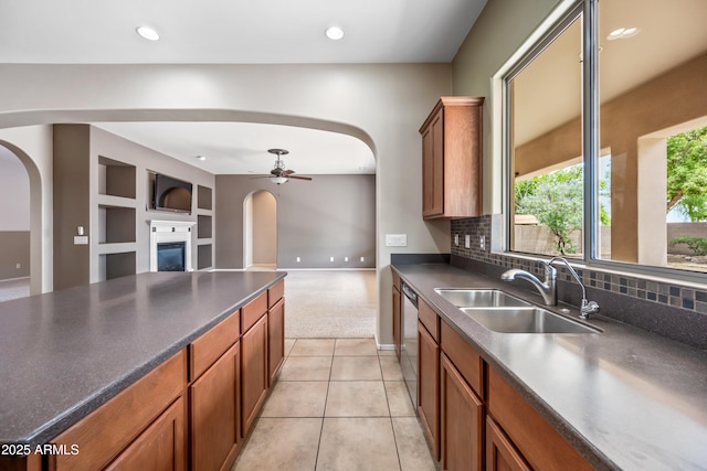 19245 W Pasadena Ave, Litchfield Park, AZ 85340 - kitchen featuring arched walkways, a sink, dark countertops, a glass covered fireplace, and recessed lighting