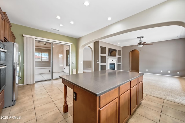 19245 W Pasadena Ave, Litchfield Park, AZ 85340 - kitchen with arched walkways, freestanding refrigerator, light tile patterned floors, ceiling fan, and a center island