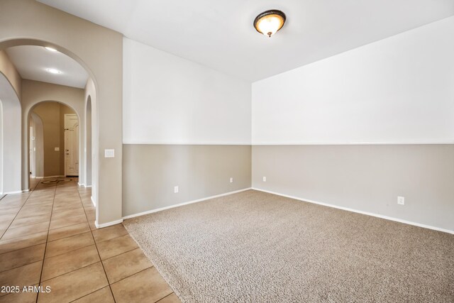 19245 W Pasadena Ave, Litchfield Park, AZ 85340 - empty room with arched walkways, light tile patterned flooring, baseboards, and light carpet