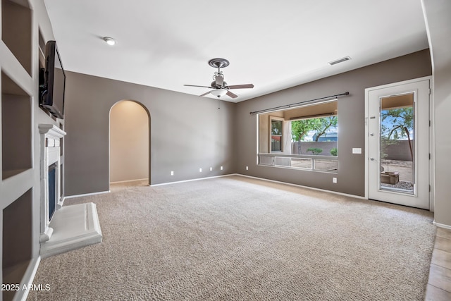 19245 W Pasadena Ave, Litchfield Park, AZ 85340 - unfurnished living room with ceiling fan, arched walkways, a fireplace with raised hearth, and baseboards