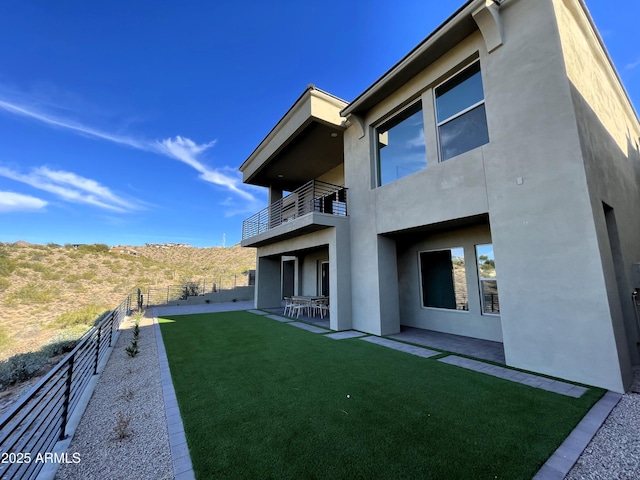 back of property featuring a balcony, a yard, and a patio