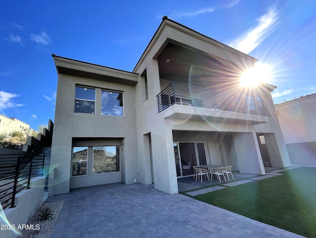 back of house featuring a balcony, a patio area, and a lawn