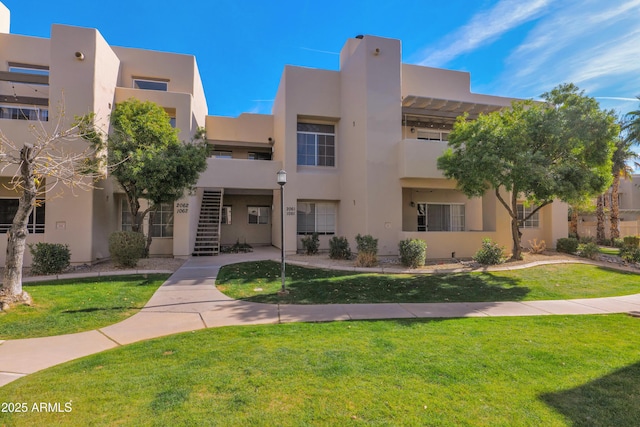 pueblo revival-style home with a front lawn