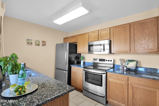 kitchen featuring appliances with stainless steel finishes, dark stone counters, and light tile patterned floors