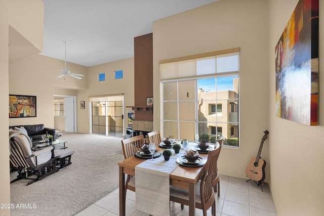 dining space with light carpet, high vaulted ceiling, and ceiling fan