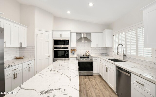 13620 N 80th Pl, Scottsdale, AZ 85260 - kitchen featuring stainless steel appliances, wall chimney range hood, a sink, vaulted ceiling, and white cabinets