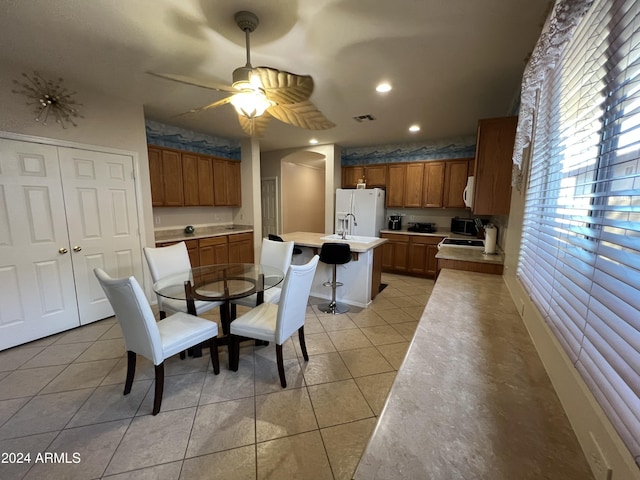 tiled dining room with ceiling fan and sink