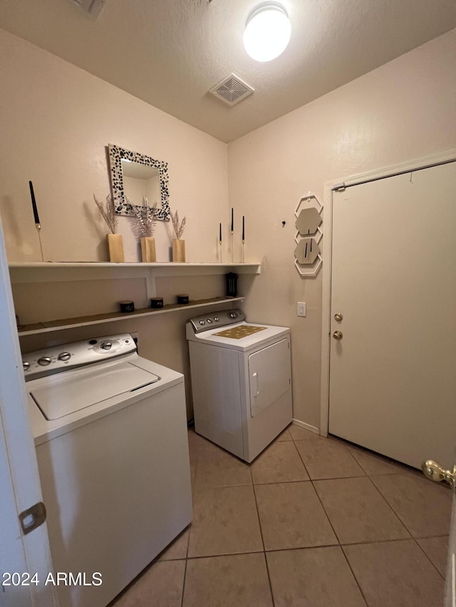 washroom featuring light tile patterned flooring, cabinets, a textured ceiling, and washing machine and clothes dryer