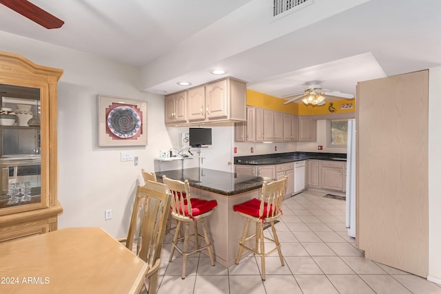 kitchen featuring ceiling fan, light tile patterned floors, light brown cabinetry, kitchen peninsula, and a breakfast bar area