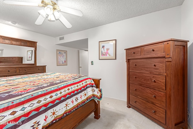 carpeted bedroom featuring ceiling fan and a textured ceiling