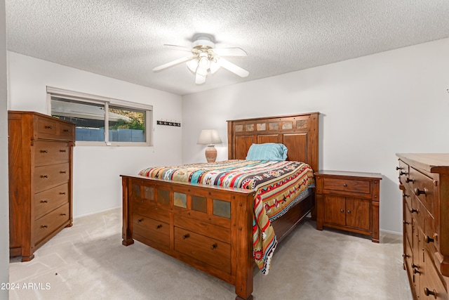 bedroom with ceiling fan, light colored carpet, and a textured ceiling