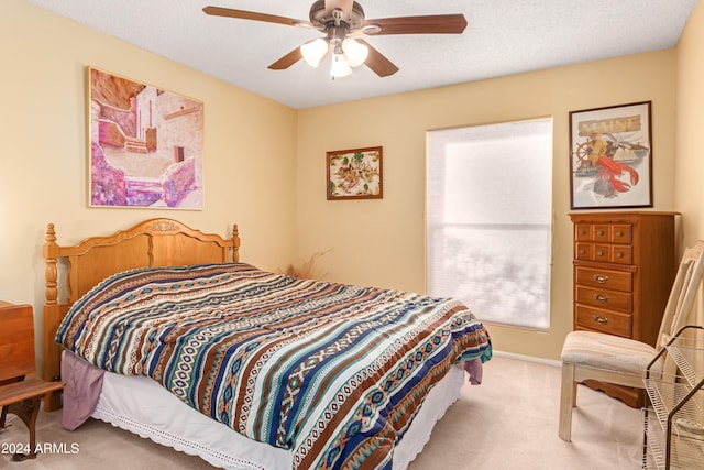 bedroom with a textured ceiling, ceiling fan, and light carpet