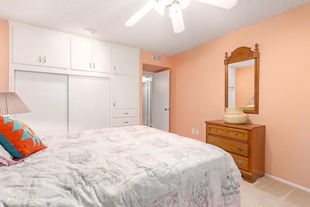 carpeted bedroom with a textured ceiling, a closet, and ceiling fan