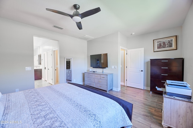 bedroom with ensuite bathroom, light wood-type flooring, and ceiling fan