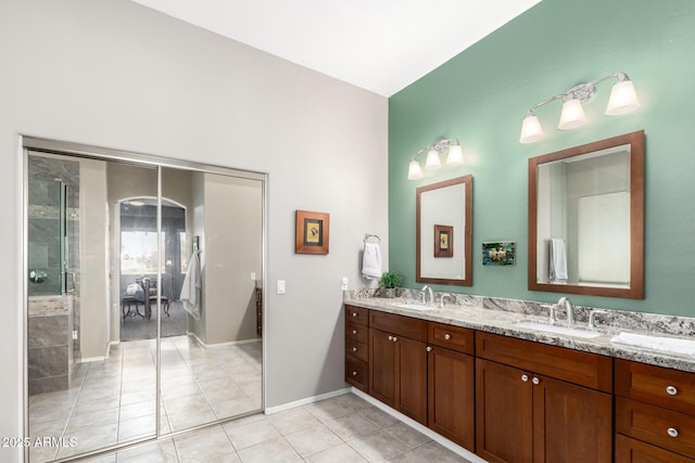 full bathroom with double vanity, tile patterned flooring, and a sink