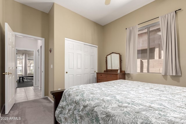carpeted bedroom with a closet, tile patterned flooring, a ceiling fan, and baseboards