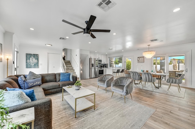 living room with ceiling fan with notable chandelier, light hardwood / wood-style floors, and ornamental molding