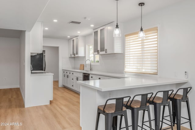 kitchen featuring white cabinetry, appliances with stainless steel finishes, light hardwood / wood-style floors, and kitchen peninsula