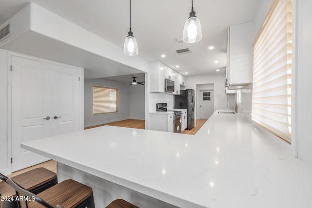 kitchen featuring kitchen peninsula, sink, tasteful backsplash, white cabinetry, and appliances with stainless steel finishes