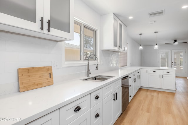 kitchen with white cabinets, sink, stainless steel dishwasher, pendant lighting, and light wood-type flooring