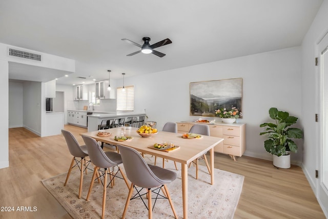 dining room featuring ceiling fan, sink, and light hardwood / wood-style flooring