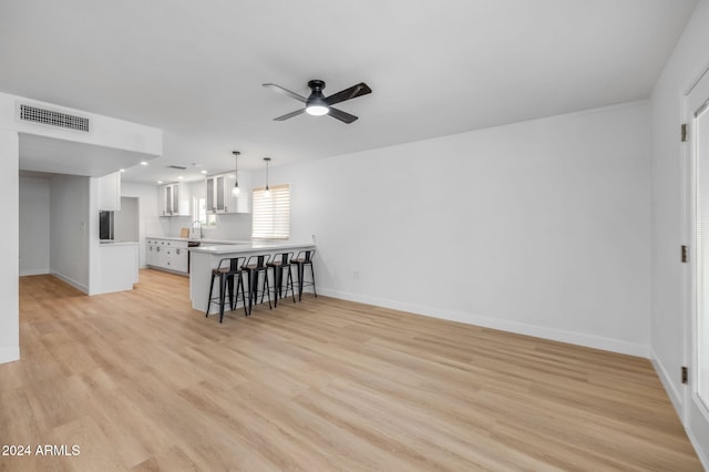 living room with ceiling fan, sink, and light wood-type flooring