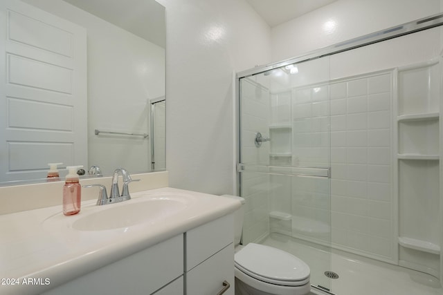 bathroom with vanity, toilet, and a shower with door