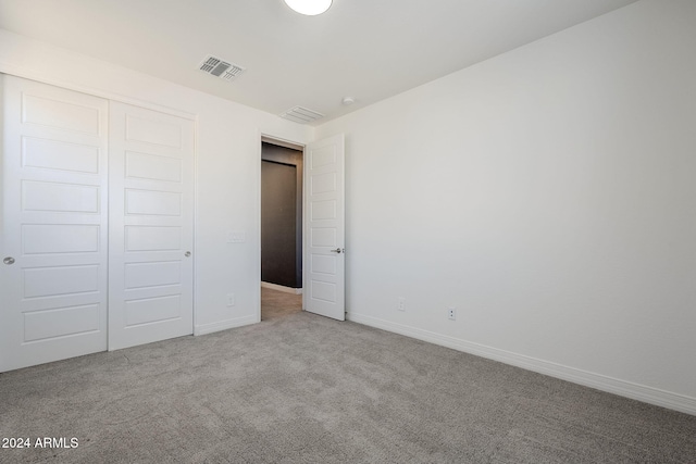 unfurnished bedroom featuring light colored carpet and a closet