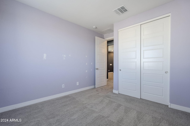 unfurnished bedroom with light colored carpet and a closet