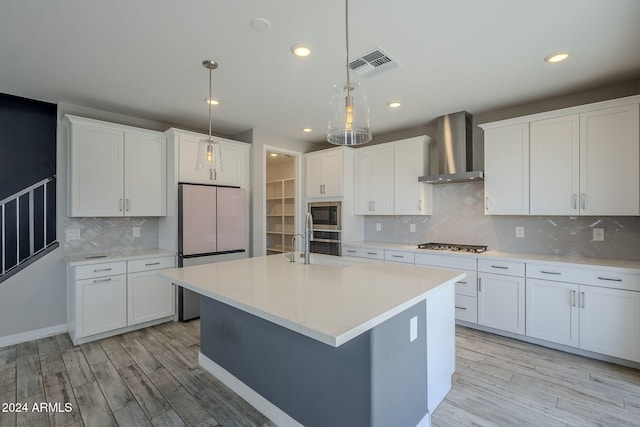 kitchen featuring decorative backsplash, light hardwood / wood-style flooring, wall chimney exhaust hood, and hanging light fixtures